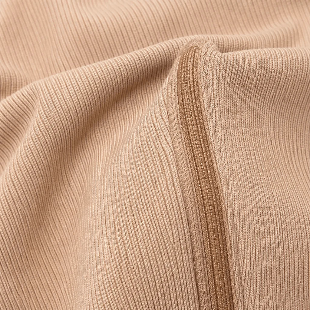 Close-up of the beige ribbed fabric and integrated zipper of a compression sock.