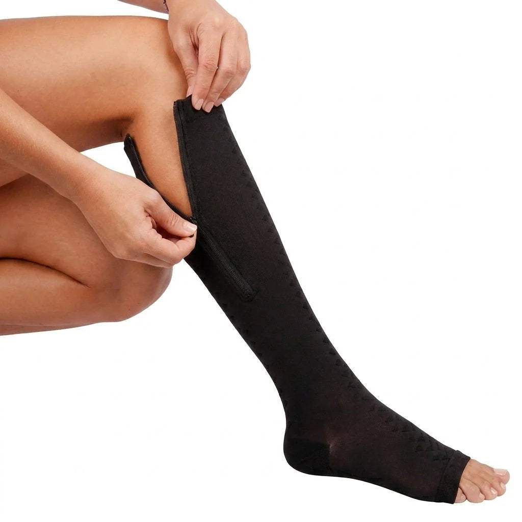 A person's hands zipping up a black, open-toe compression sock on their lower leg.