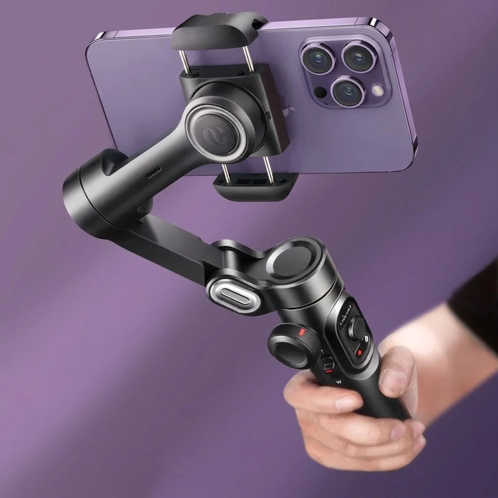 A hand holding a black 3-axis phone gimbal stabilizer with a purple smartphone attached against a purple background.