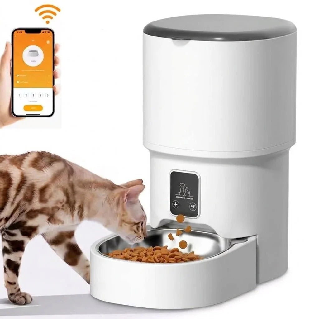 A white automatic cat feeder dispensing dry food into a metal bowl, with a smartphone app interface shown above.