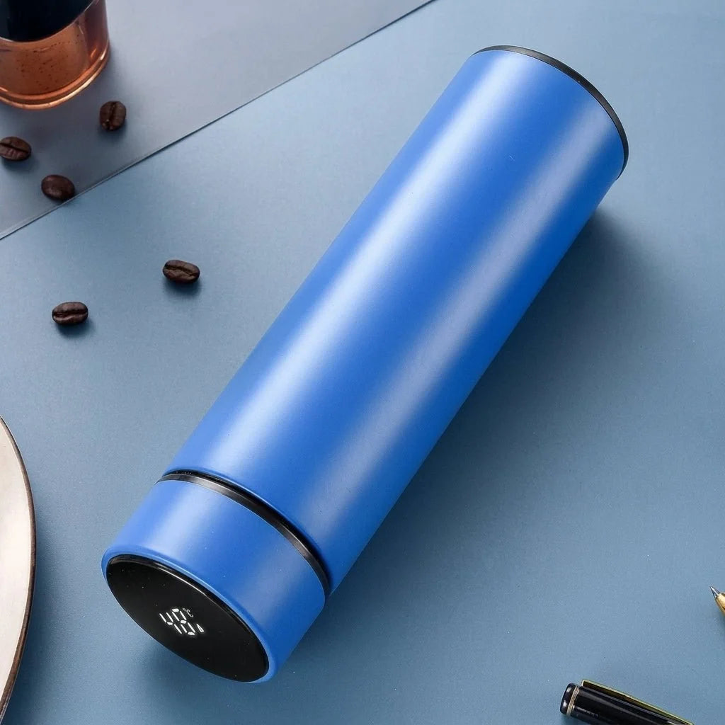 A sleek blue stainless steel insulated water bottle with a digital LED temperature display on the lid, set on a blue desk.
