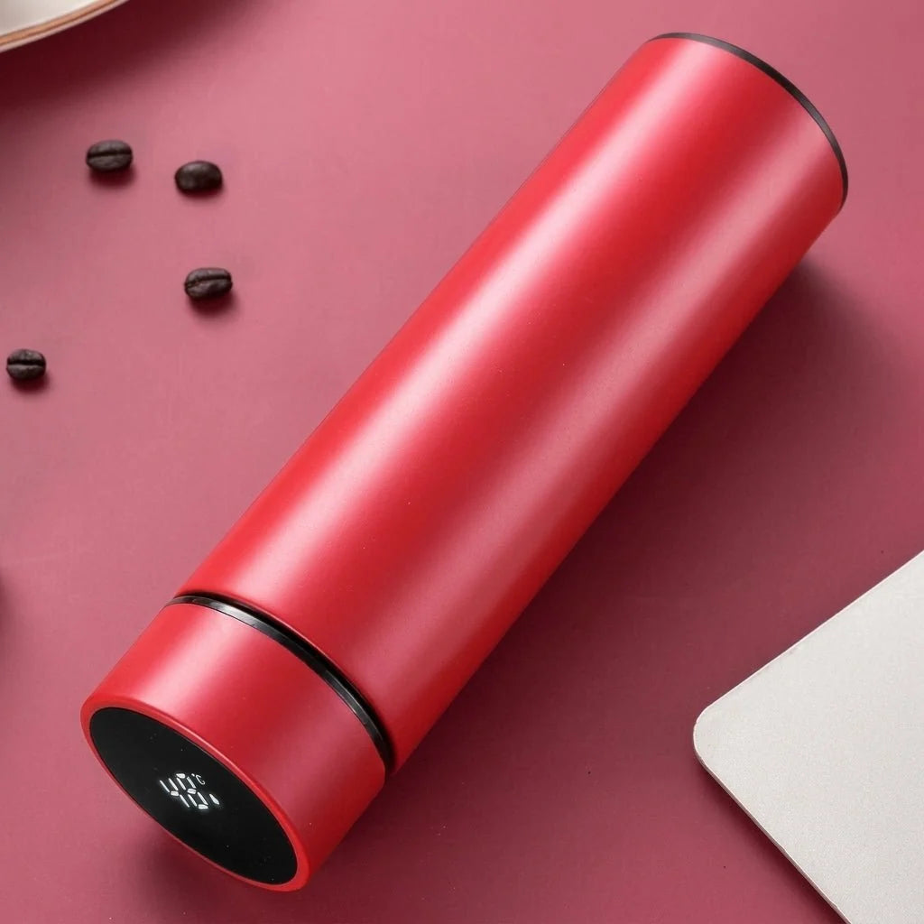 A sleek red stainless steel insulated water bottle with a digital LED temperature display on the lid, set on a desk.