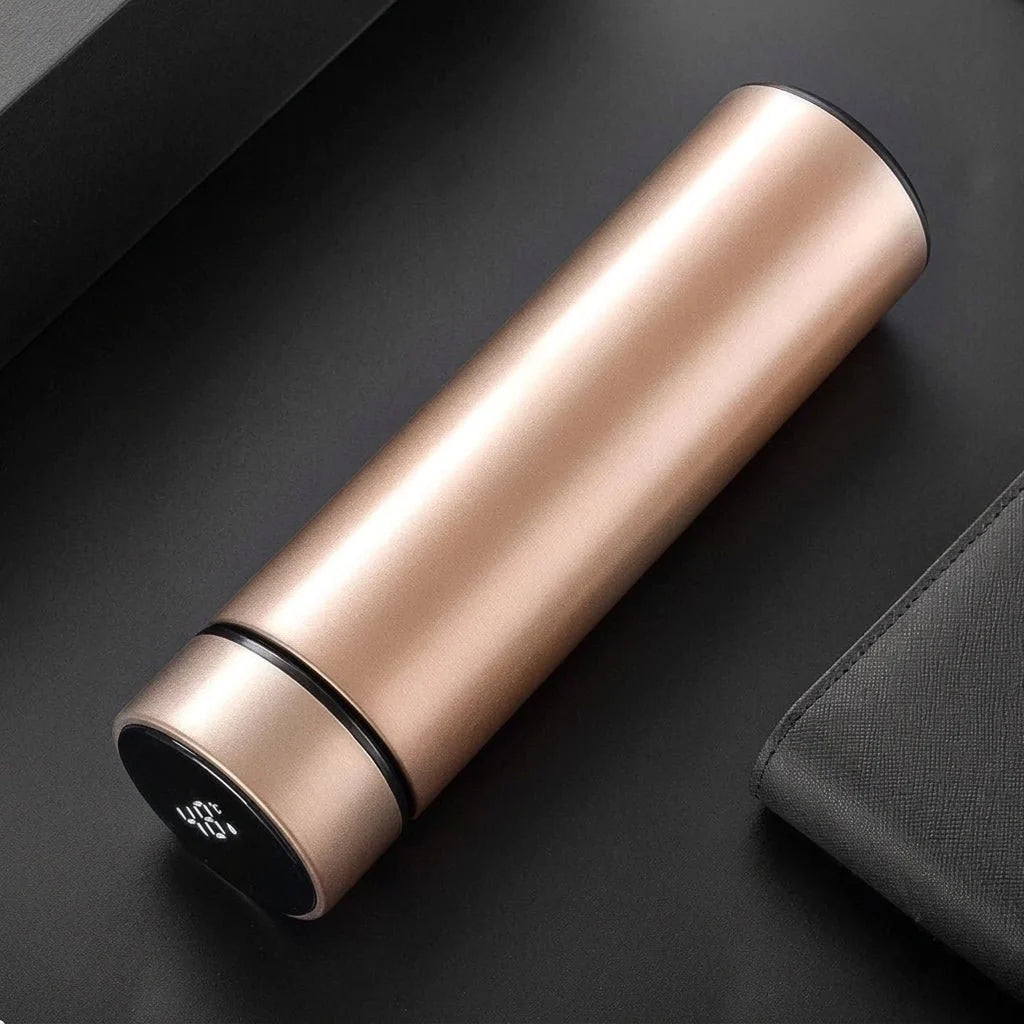 A rose gold stainless steel insulated water bottle with a digital LED temperature display on the lid, set on a dark surface.