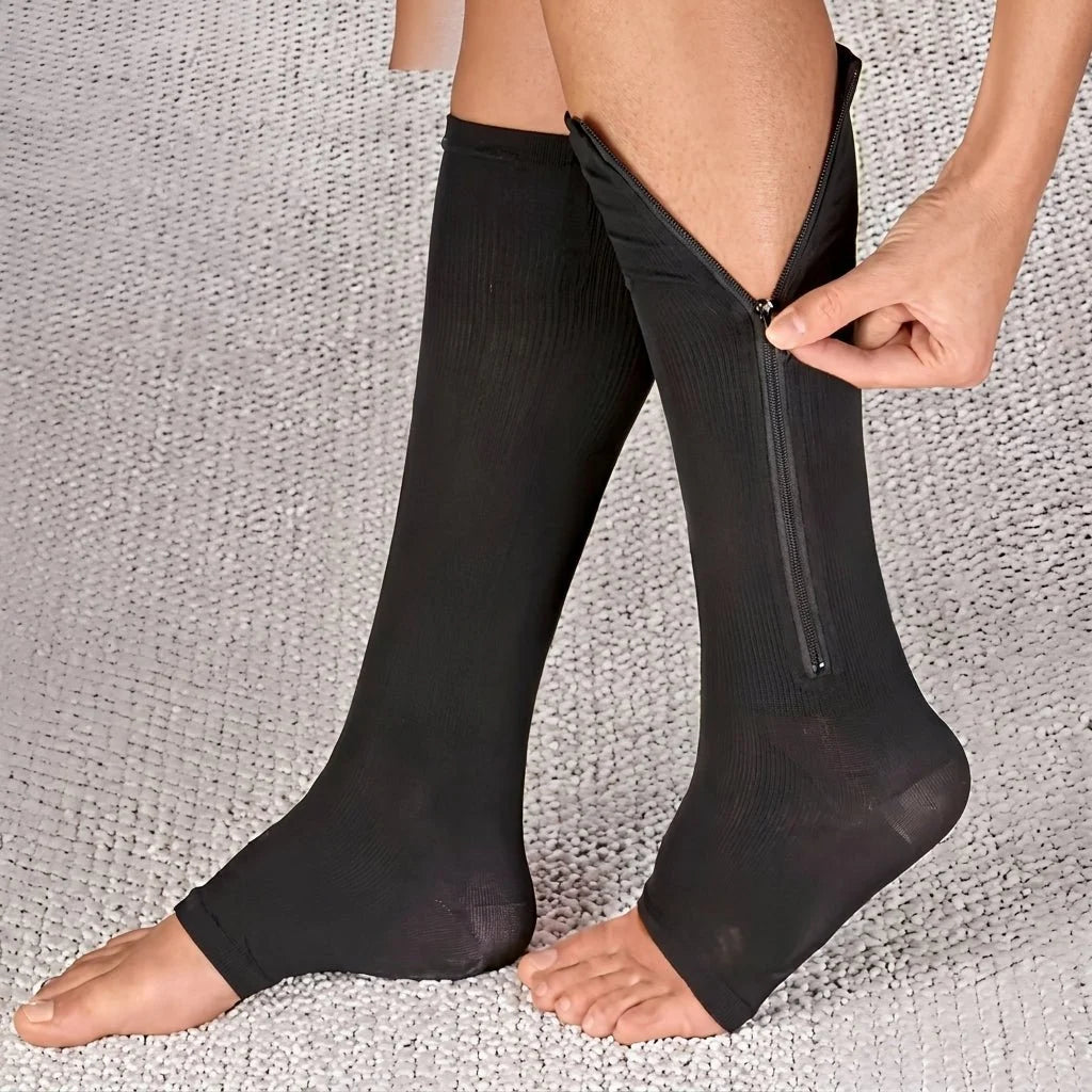 A person putting on black open-toe compression socks with a side zipper for easier application.