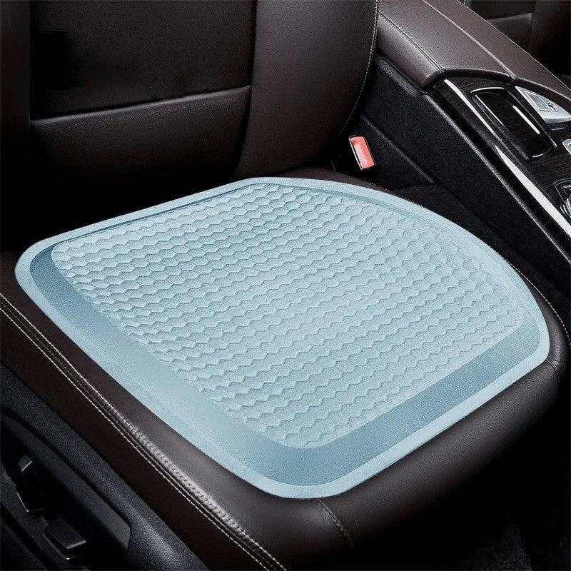 A light blue, textured gel seat cushion placed on a dark leather car seat.