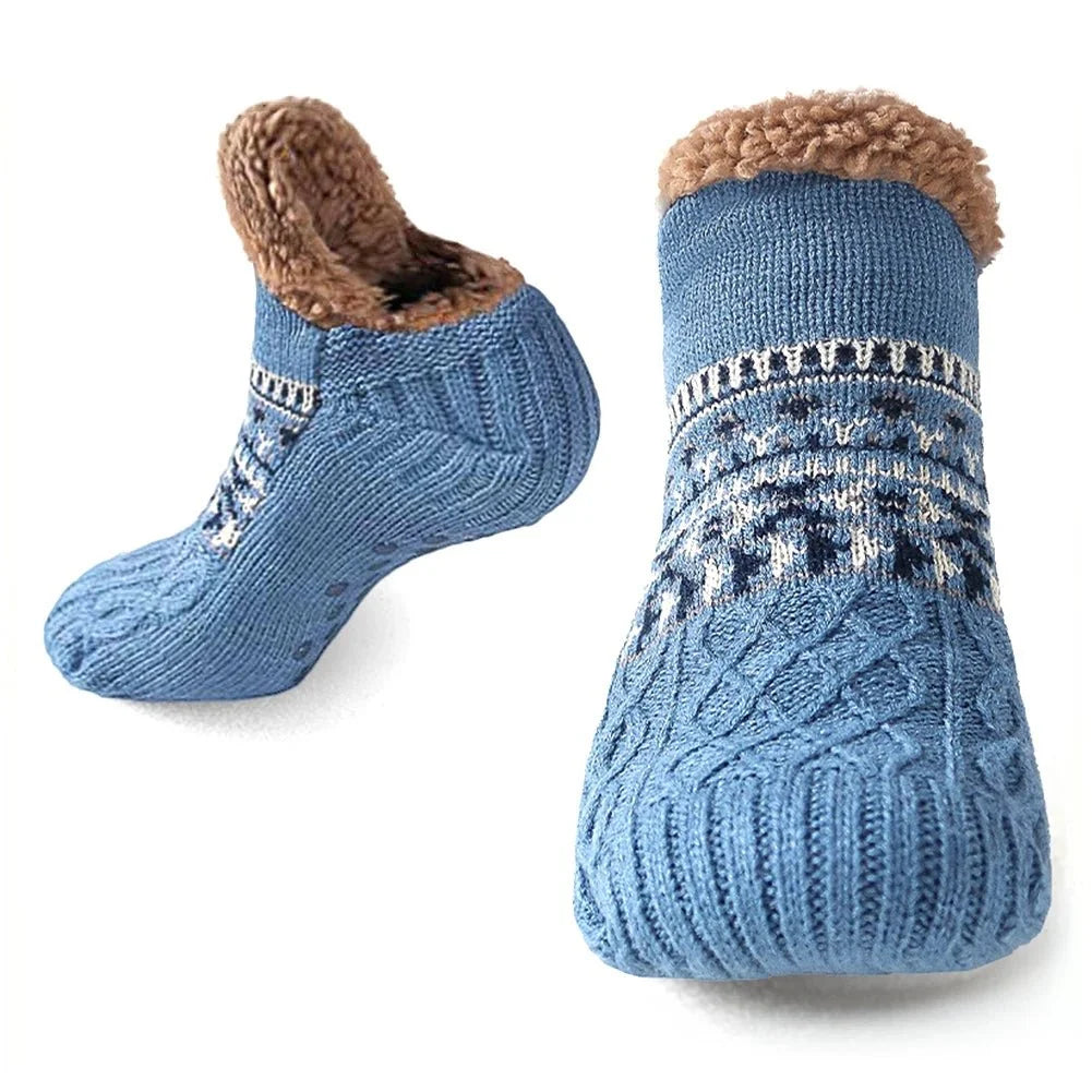 A pair of blue, cable-knit fleece-lined grip socks shown from the side and front, featuring a textured anti-slip sole.