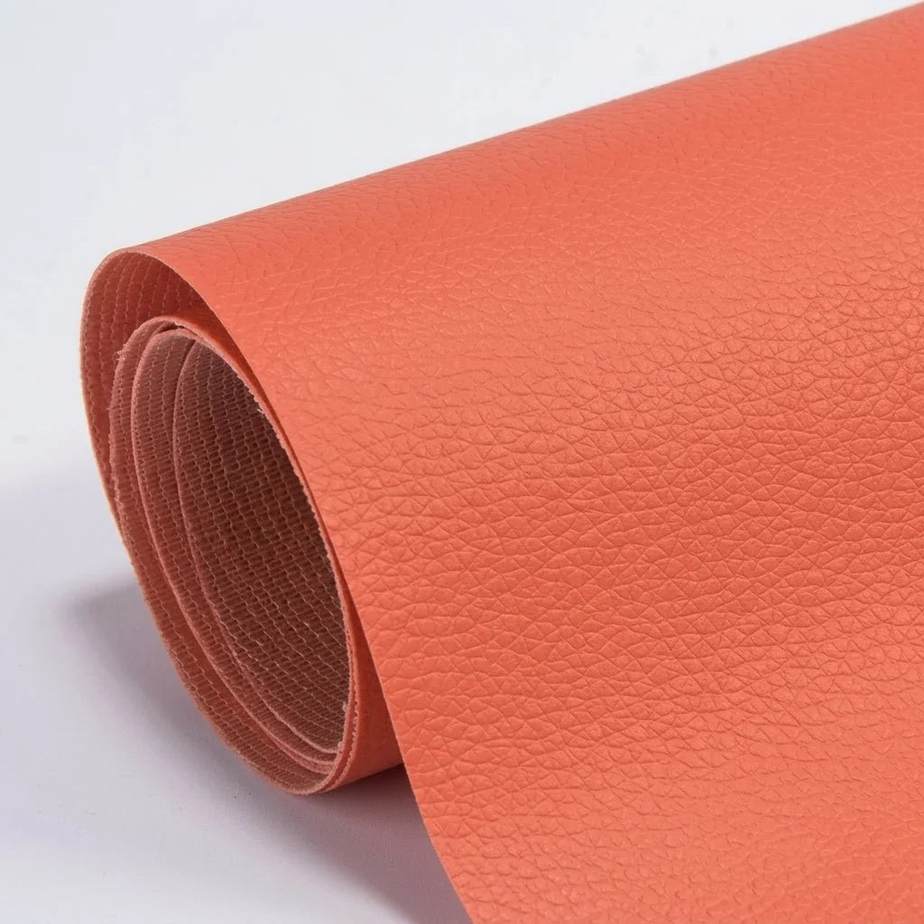 A roll of coral-coloured, textured self-adhesive leather repair patch material on a white background.