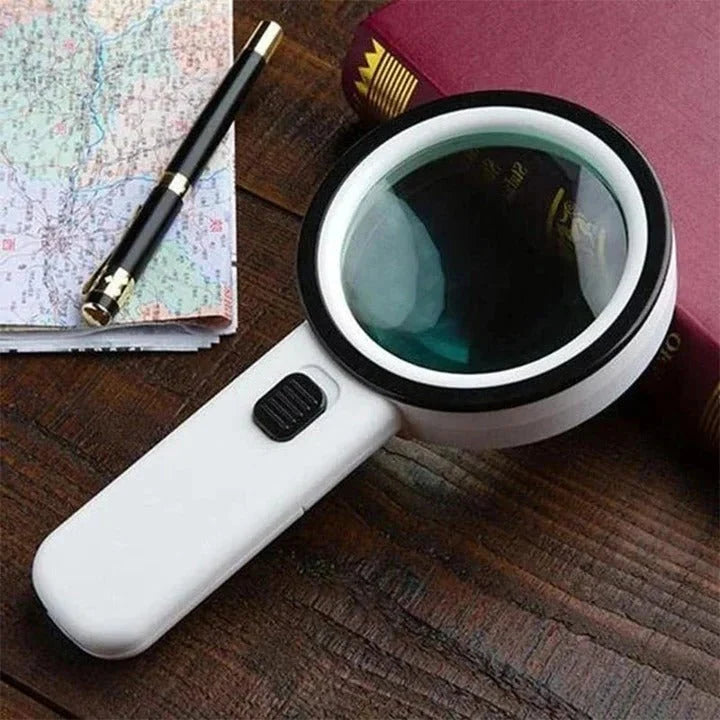A white handheld magnifying glass with an LED light, resting on a wooden table next to a map and a book.