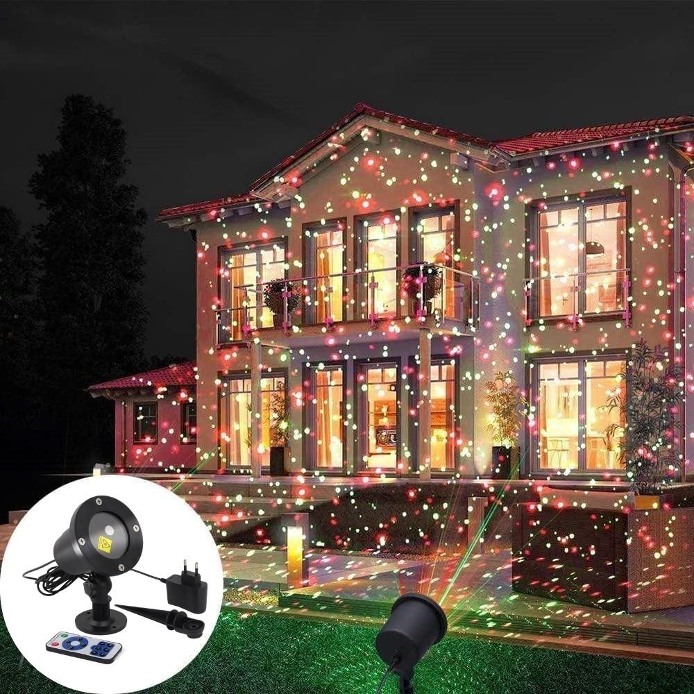 A house facade illuminated at night by a festive outdoor laser projector displaying red and green light patterns.