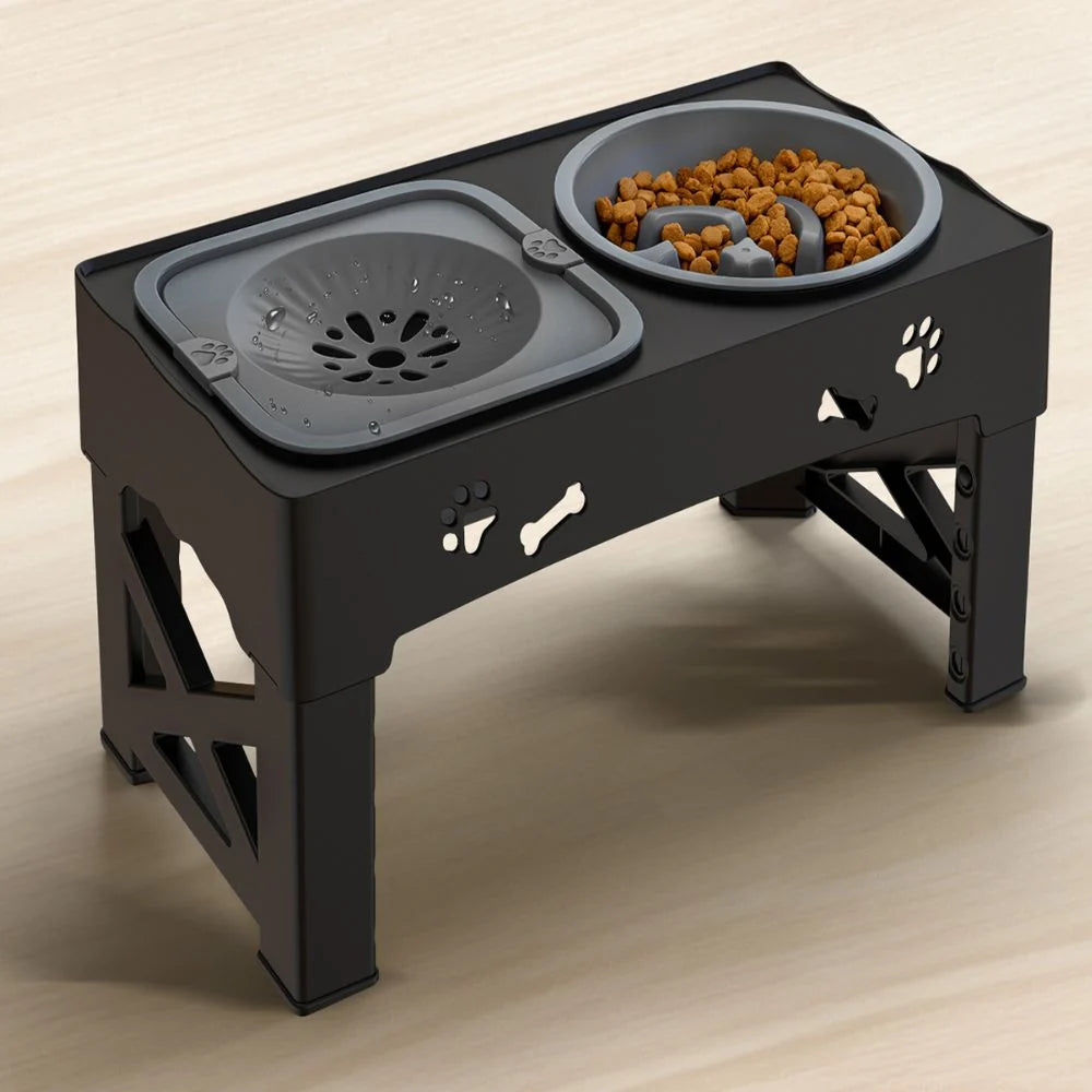 An elevated black dog feeder with an adjustable stand, featuring a grey splash-proof water bowl and a slow-feeder food bowl.