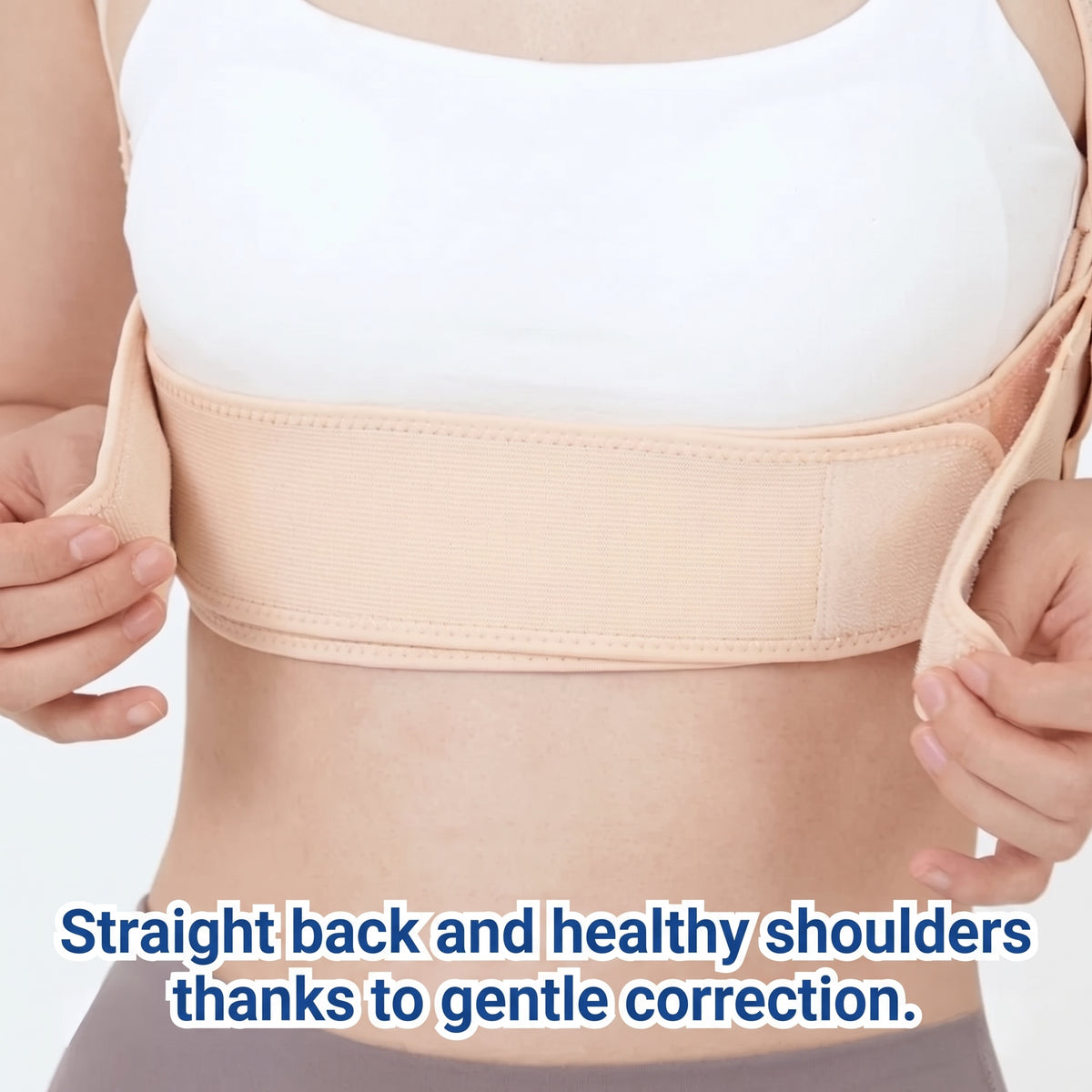 A person wearing a beige adjustable back posture corrector brace over a white top, focusing on spinal alignment.