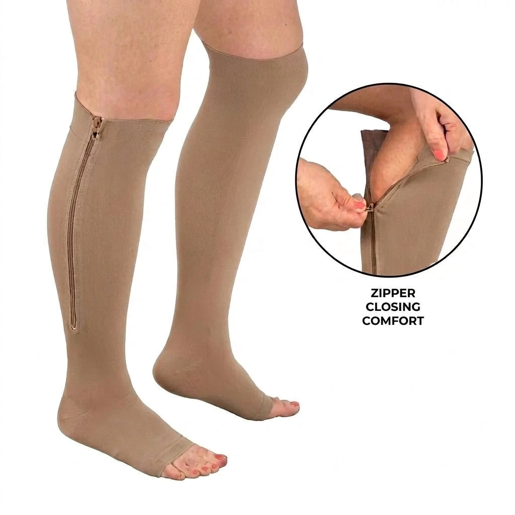 A pair of beige open-toe compression socks with a side zipper being fastened by hands, shown on a white background.