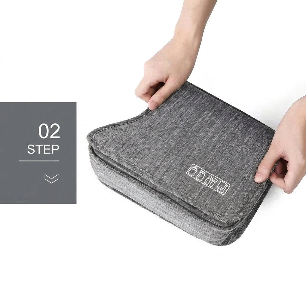 A pair of hands holding a grey, fabric-textured, square-shaped toiletry bag with a white icon of toiletries on the front.